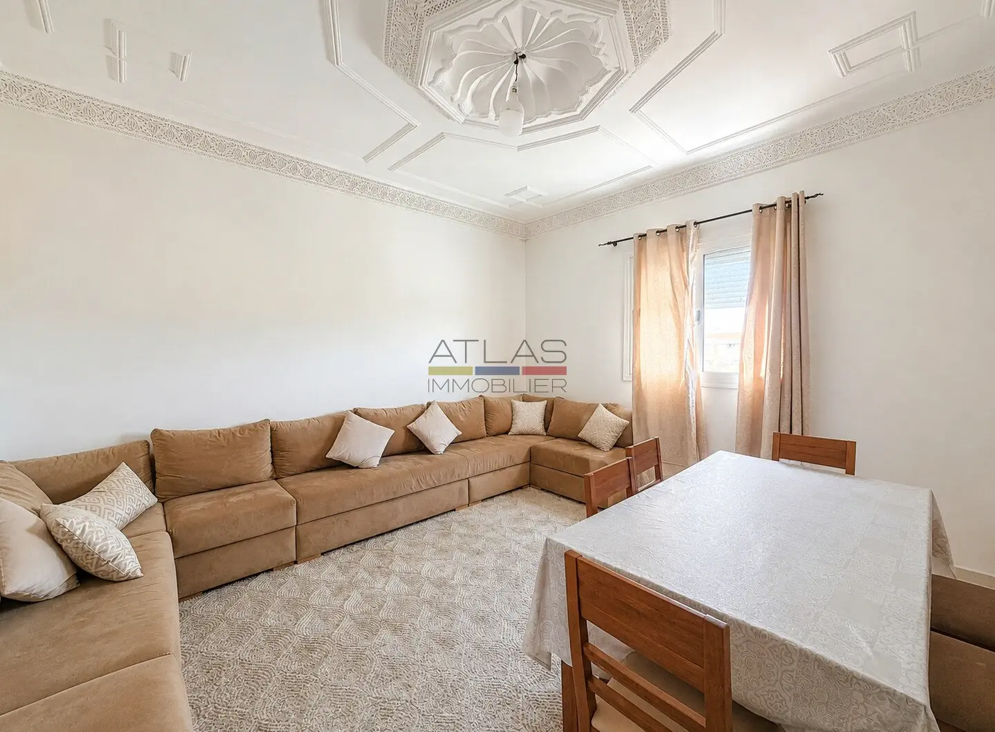 Bright furnished living room with a corner sofa and sculpted ceiling in Erraounak, Essaouira.