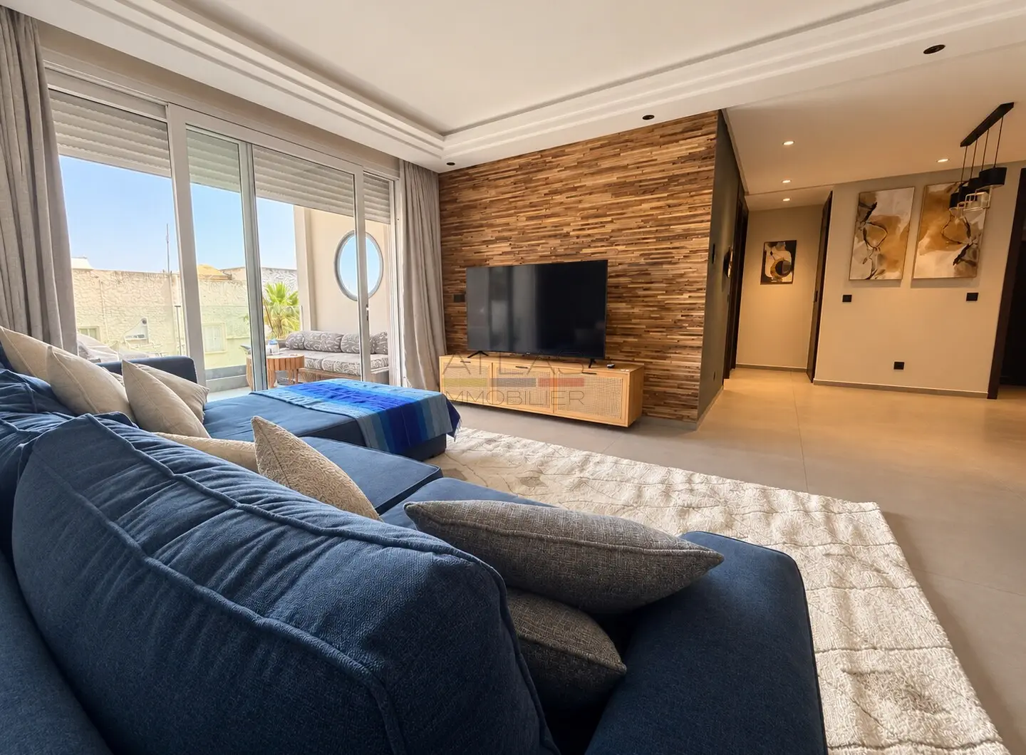Salon avec télévision et mur décoratif en bois à Essaouira