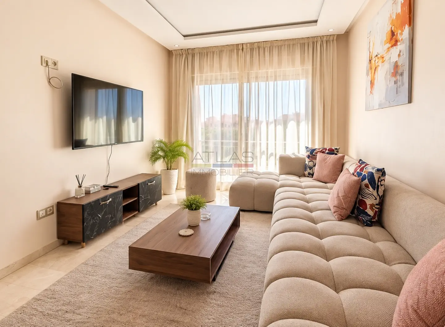 Salon avec canapé d’angle et grande baie vitrée dans un appartement à Marrakech