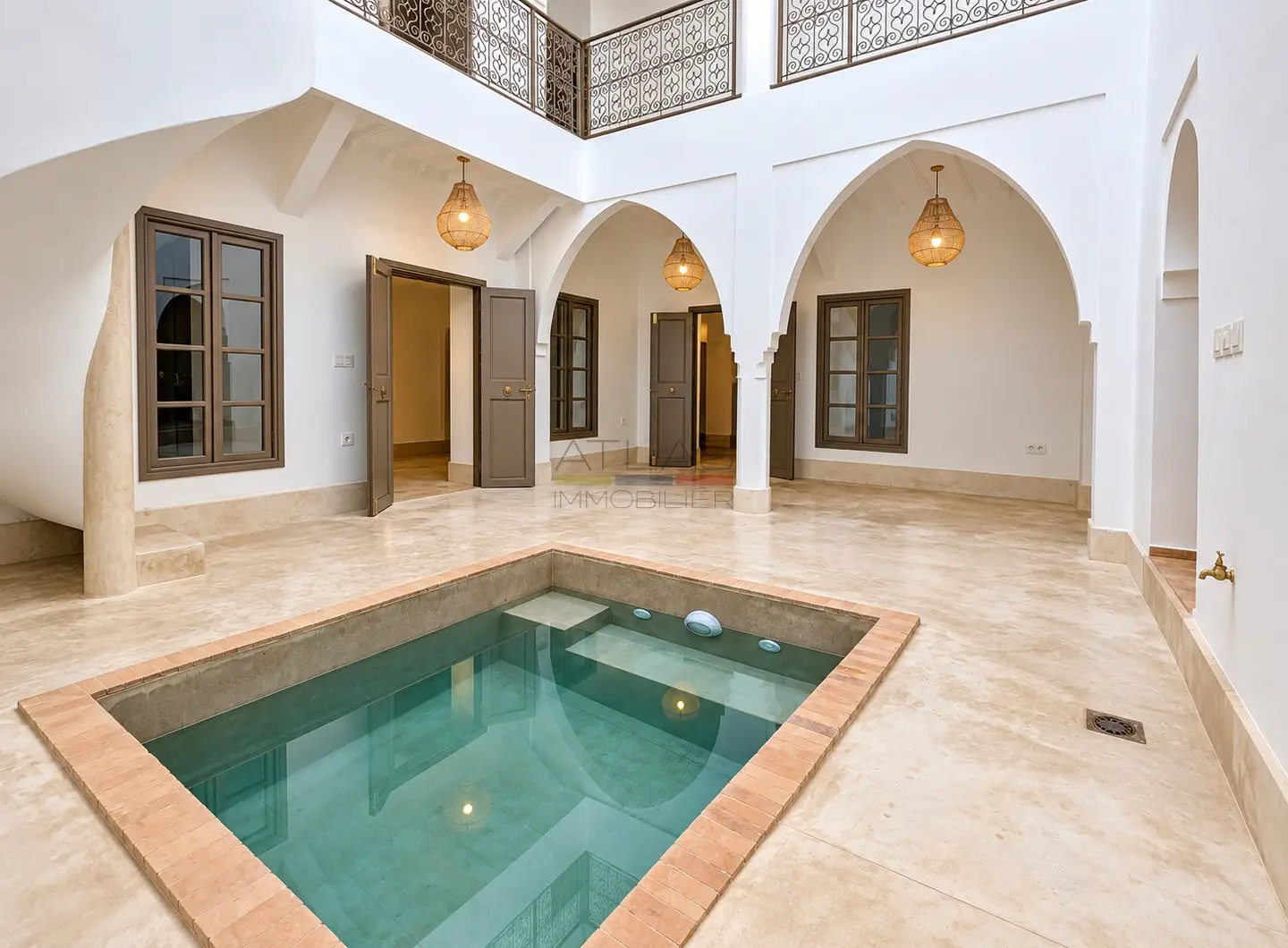 Patio lumineux d’un riad neuf à Marrakech avec bassin central et arches traditionnelles