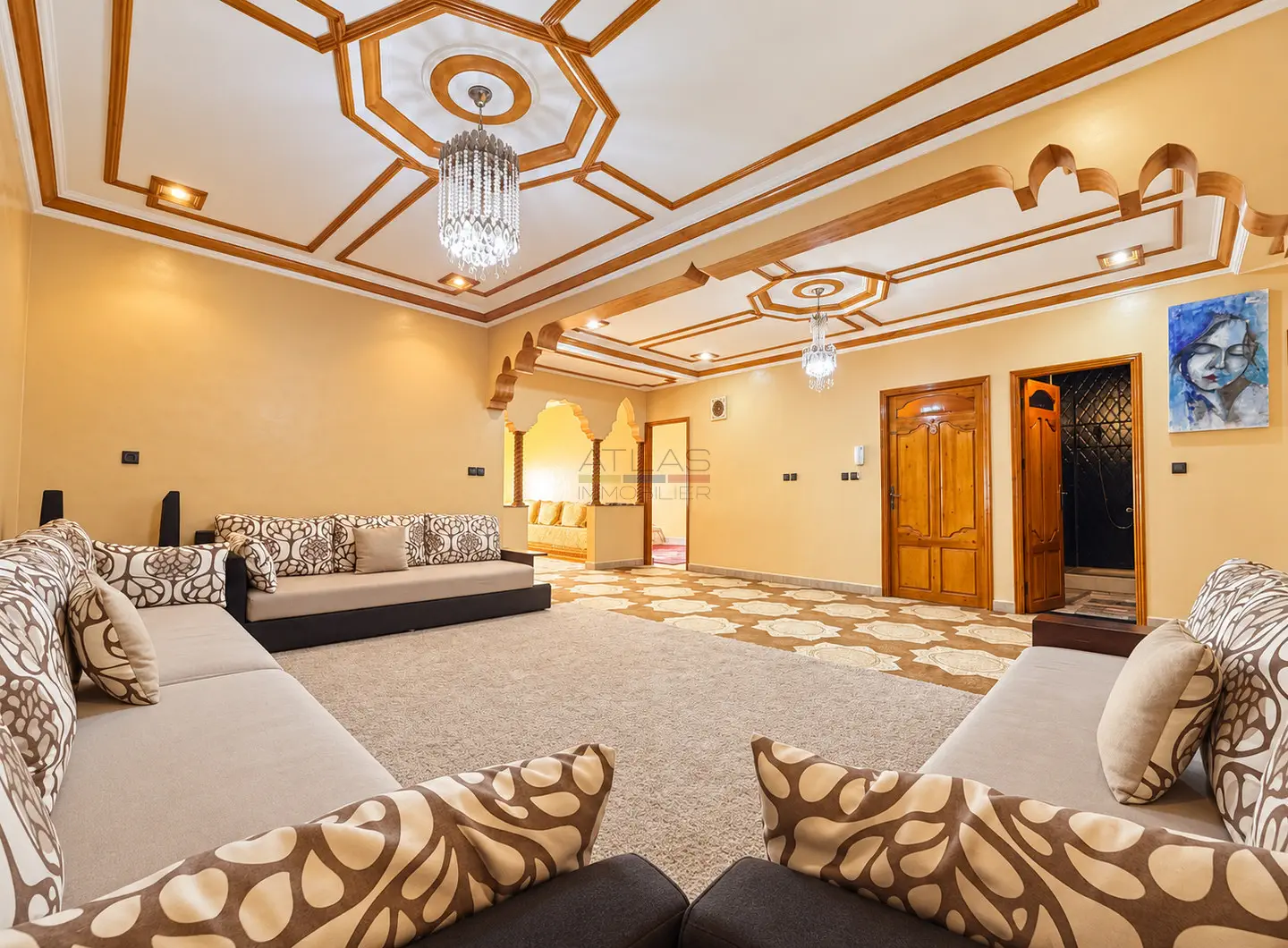 Grand salon de réception avec canapés, plafonds décoratifs et boiseries dans un appartement à Erraounak, Essaouira.